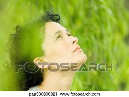 Young woman looking up, green in foreground and background View Large Photo Image Stock Image - Young woman looking up, green in foreground and background. Fotosearch