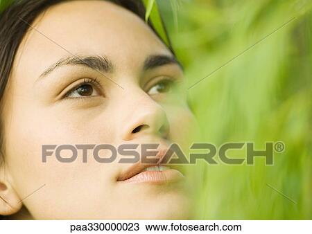 Young woman's face, green blur in foreground View Large Photo Image Stock Image - Young woman's face, green blur in foreground. Fotosearch