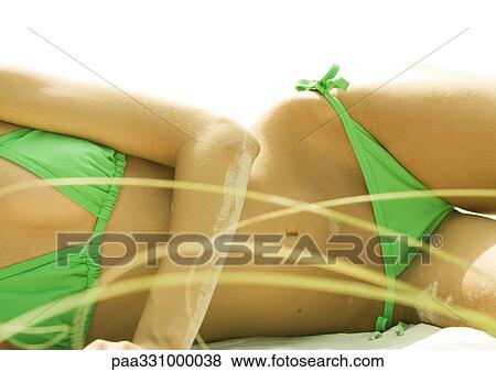 Stock Photo - Woman lying on beach in bikini, mid section. Fotosearch
