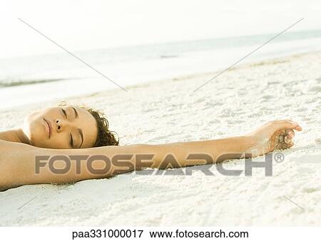 Stock Photo - Woman lying on sand, view of head and arm. Fotosearch