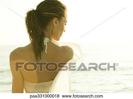 Stock Photo - Woman standing near ocean, rear view. Fotosearch