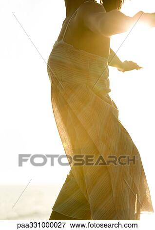 Stock Photo - Woman wearing light dress in sun, cropped. Fotosearch