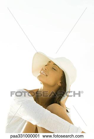 Stock Image - Woman wearing sun hat, smiling with eyes closed. Fotosearch