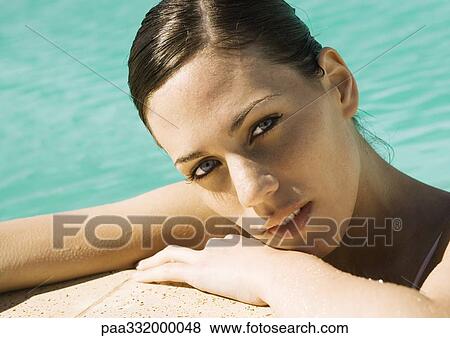 Stock Photo - Woman leaning on side of pool, close-up. Fotosearch