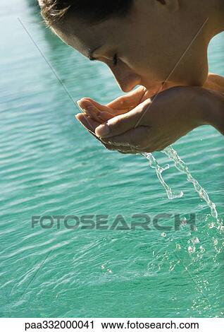 Woman leaning over water, cupping water to face View Large Photo Image Stock Image - Woman leaning over water, cupping water to face. Fotosearch