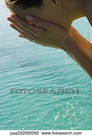 Woman leaning over water, cupping water to face View Large Photo Image Stock Image - Woman leaning over water, cupping water to face. Fotosearch