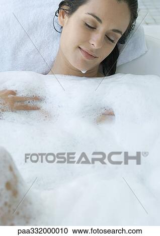 Stock Image - Woman reclining in bubble bath. Fotosearch