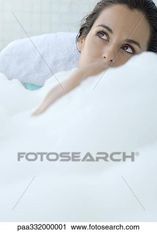 Stock Image - Woman taking bubble bath, looking up. Fotosearch