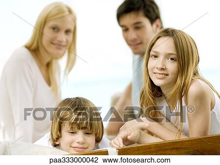 Stock Image - Boy and girl, parents in background. Fotosearch