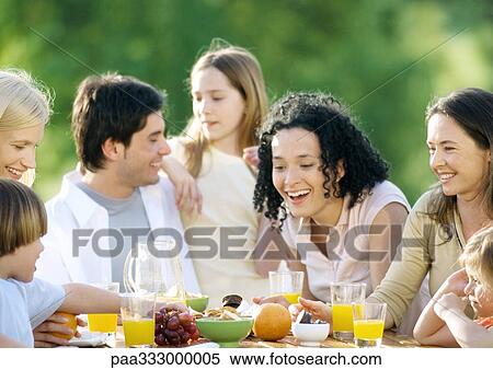 Stock Photography - Family sitting around table outdoors. Fotosearch