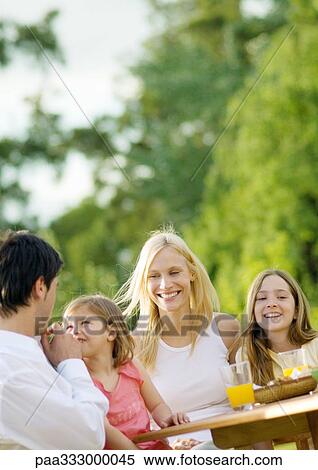Stock Photography - Family sitting at table outside. Fotosearch