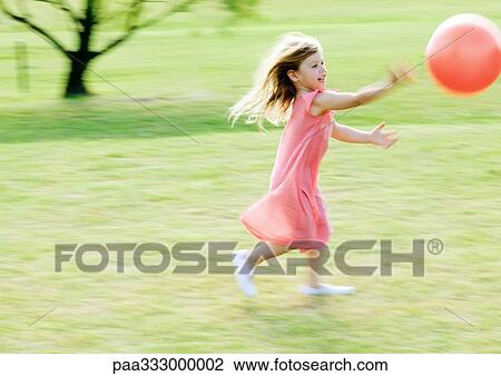 Stock Image - Girl chasing ball, blurred motion. Fotosearch