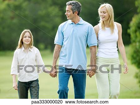 Stock Image - Girl taking walk with parents. Fotosearch