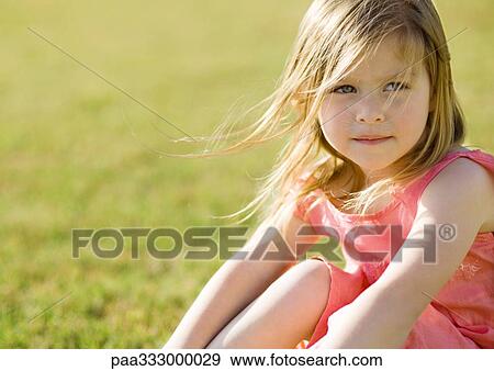Little girl sitting on grass, hair blowing in wind View Large Photo Image Stock Photo - Little girl sitting on grass, hair blowing in wind. Fotosearch