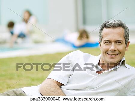 Stock Image - Man relaxing in yard. Fotosearch