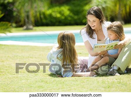 Stock Photo - Mother reading book to two daughters. Fotosearch