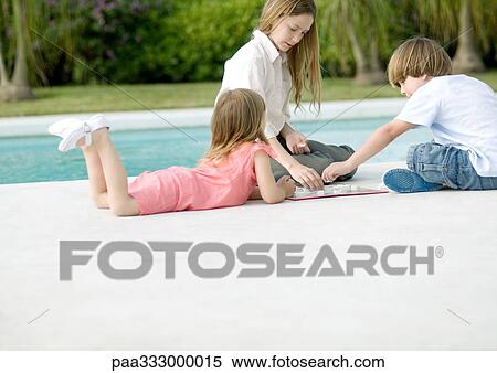 Stock Photography - Three kids playing boardgame by edge of pool. Fotosearch