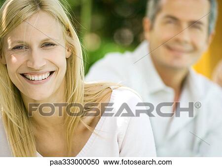 Woman smiling, man in background, portrait View Large Photo Image Stock Image - Woman smiling, man in background, portrait. Fotosearch