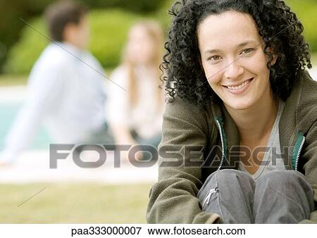 Young woman sitting with knees up, smiling View Large Photo Image Stock Photo - Young woman sitting with knees up, smiling. Fotosearch