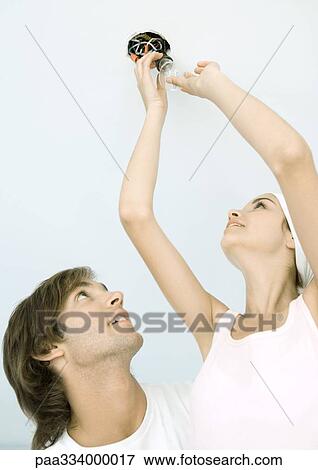 Couple changing lightbulb View Large Photo Image Stock Photo - Couple changing lightbulb. Fotosearch