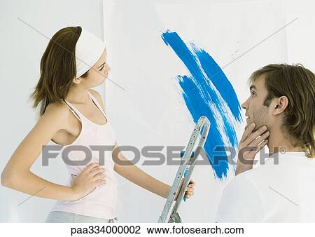 Stock Image - Couple deciding on paint color. Fotosearch