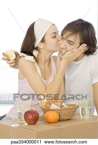Couple having breakfast on cardboard box, woman kissing man's cheek View Large Photo Image Stock Image - Couple having breakfast on cardboard box, woman kissing man's cheek. Fotosearch