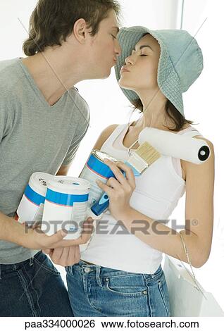 Couple holding painting supplies and kissing View Large Photo Image Stock Photograph - Couple holding painting supplies and kissing. Fotosearch