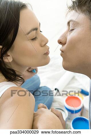 Stock Photo - Couple kissing, paint cans in background. Fotosearch