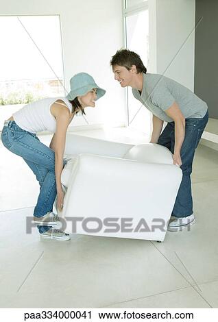 Couple moving armchair together View Large Photo Image Stock Image - Couple moving armchair together. Fotosearch