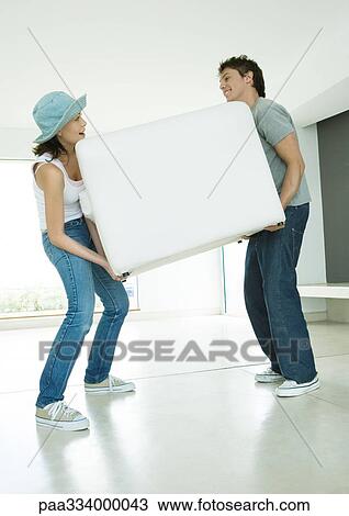 Couple moving armchair together View Large Photo Image Stock Image - Couple moving armchair together. Fotosearch