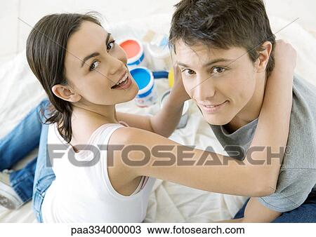 Stock Image - Couple sitting on floor surrounded by paint cans. Fotosearch