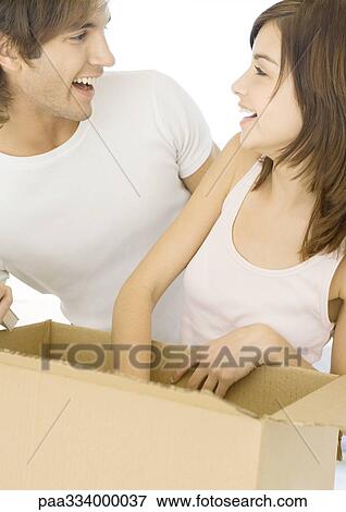 Couple unpacking cardboard box and smiling View Large Photo Image Stock Photo - Couple unpacking cardboard box and smiling. Fotosearch