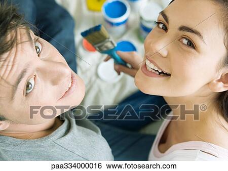 Stock Photograph - Couple with paint materials, smiling at camera. Fotosearch