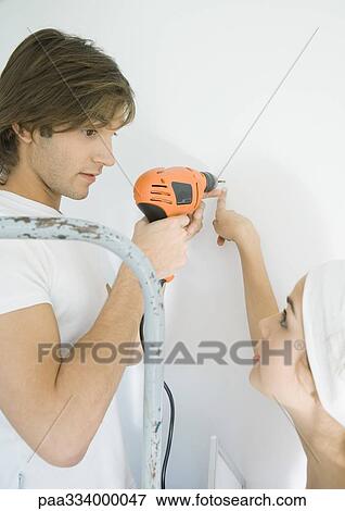 Man holding drill while woman points to wall View Large Photo Image Stock Photo - Man holding drill while woman points to wall. Fotosearch