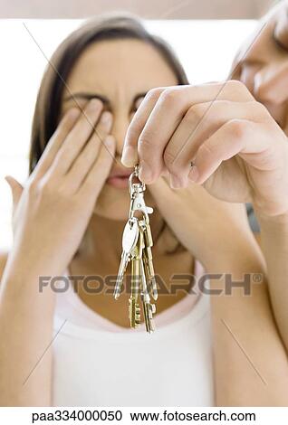 Man holds up keys while woman covers eyes View Large Photo Image Stock Image - Man holds up keys while woman covers eyes. Fotosearch