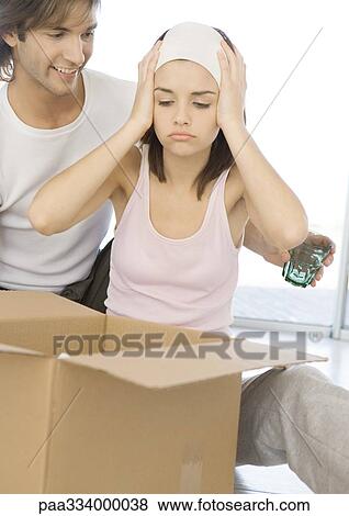 Stock Photo - Woman holding head, looking at cardboard box. Fotosearch