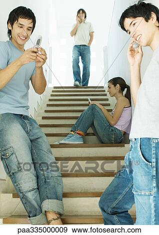 Four young adults, each using cell phone in stairway View Large Photo Image Stock Photo - Four young adults, each using cell phone in stairway. Fotosearch