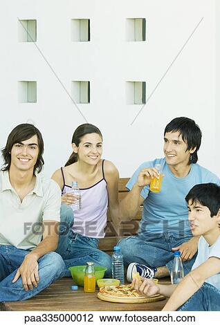 Stock Image - Group of young friends sharing meal. Fotosearch