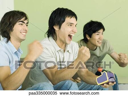 Three young men playing video games View Large Photo Image Stock Photography - Three young men playing video games. Fotosearch