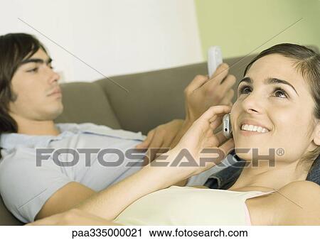 Stock Image - Two friends using cell phones. Fotosearch