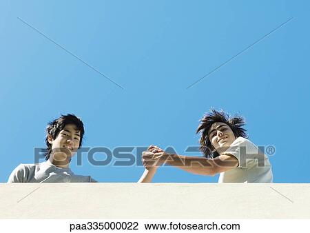 Two young male friends, low angle view View Large Photo Image Stock Image - Two young male friends, low angle view. Fotosearch