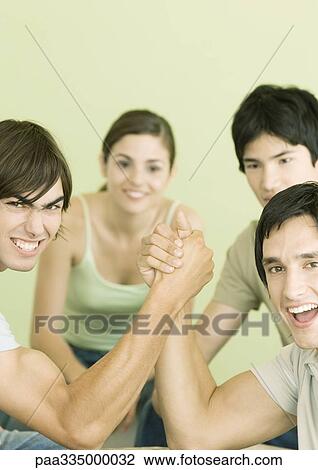 Two young men arm wrestling, friends in background View Large Photo Image Stock Image - Two young men arm wrestling, friends in background. Fotosearch