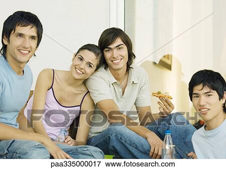Stock Photo - Young adult friends hanging out and eating together. Fotosearch