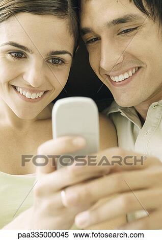 Young couple looking at cell phone View Large Photo Image Stock Photography - Young couple looking at cell phone. Fotosearch