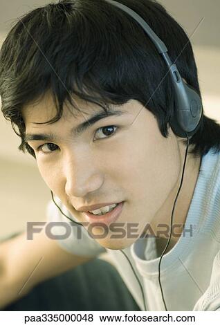 Young man listening to headphones View Large Photo Image Stock Photo - Young man listening to headphones. Fotosearch