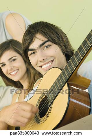 Stock Image - Young man playing guitar for friends. Fotosearch