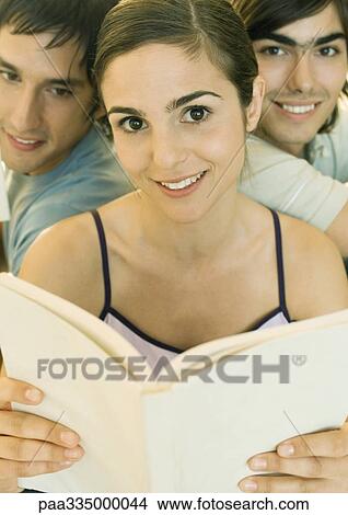 Picture - Young woman holding book, two friends in background. Fotosearch