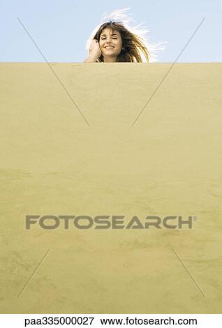 Young woman looking over wall, low angle view View Large Photo Image Stock Photo - Young woman looking over wall, low angle view. Fotosearch