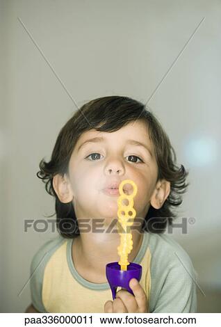 Stock Image - Boy playing, blowing soap bubbles. Fotosearch