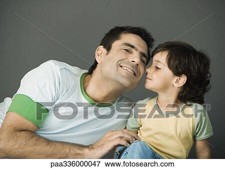 Stock Photo - Father and son sitting side by side, child kissing his father's cheek, smiling, portrait. Fotosearch